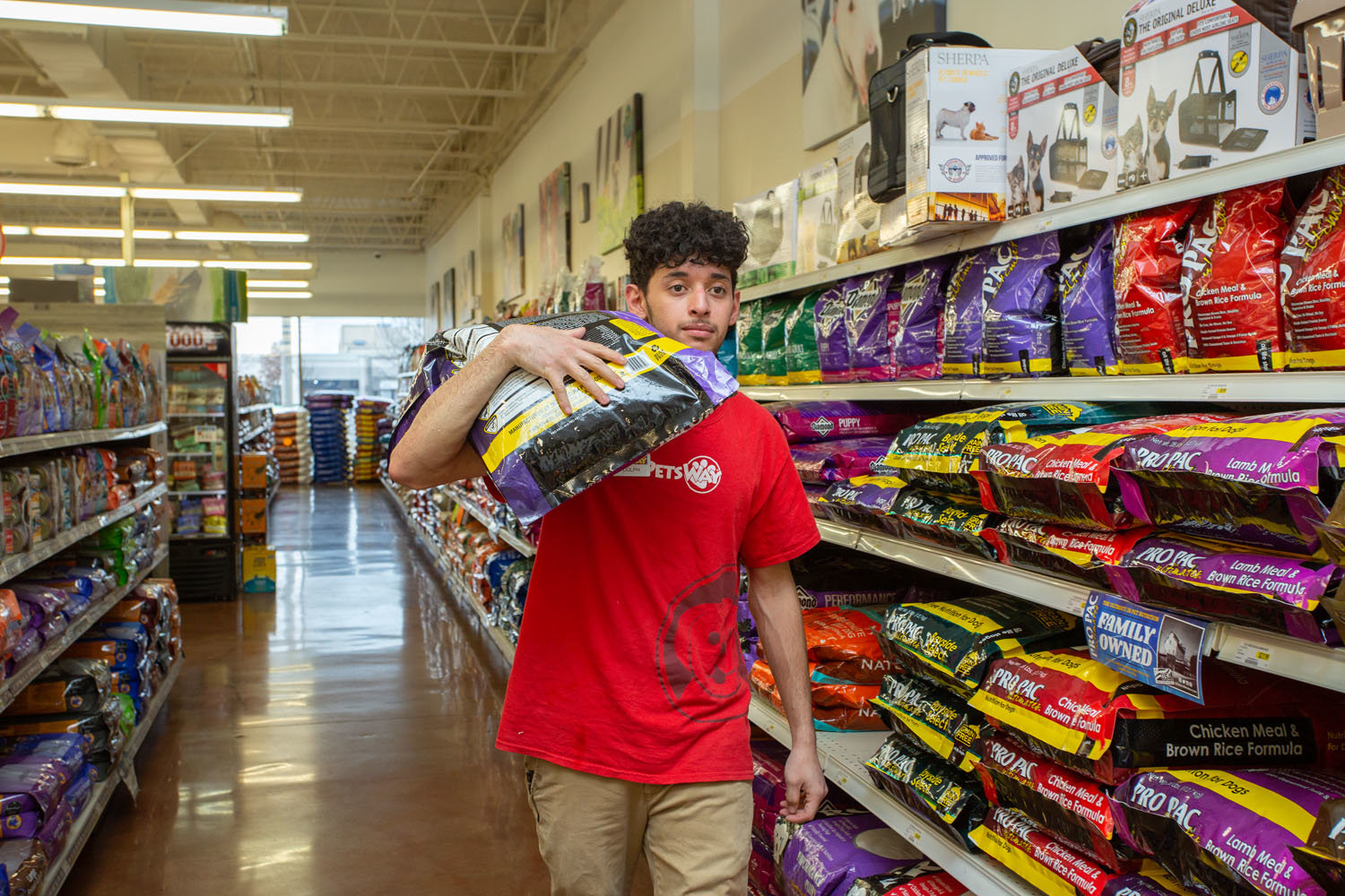 MOVING PRODUCT: Adolph Garcia, a Petsway employee, moves bags of dog food for a customers. Petsway is closing three out-of-town stores.